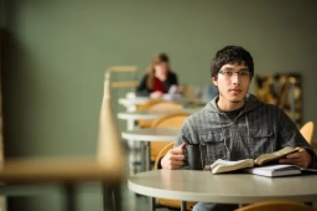 a young man sitting a table with his Bible open