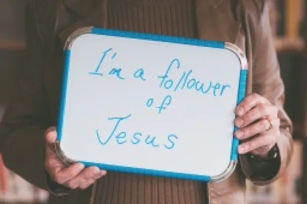 Person holding whiteboard that says "I am a Follower of Jesus"