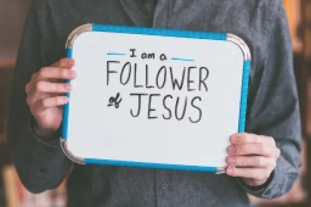 Man holding whiteboard that says "I am a Follower of Jesus"