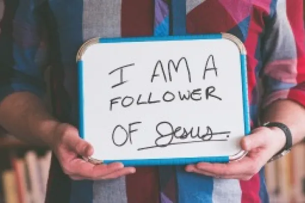 Man holding whiteboard that says "I am a Follower of Jesus"