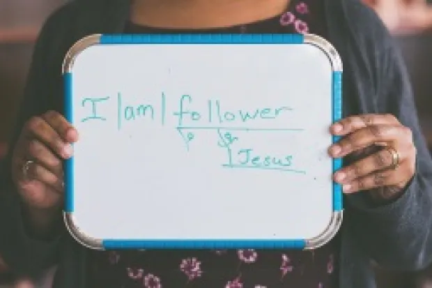 Woman holding whiteboard that says "I am a Follower of Jesus"