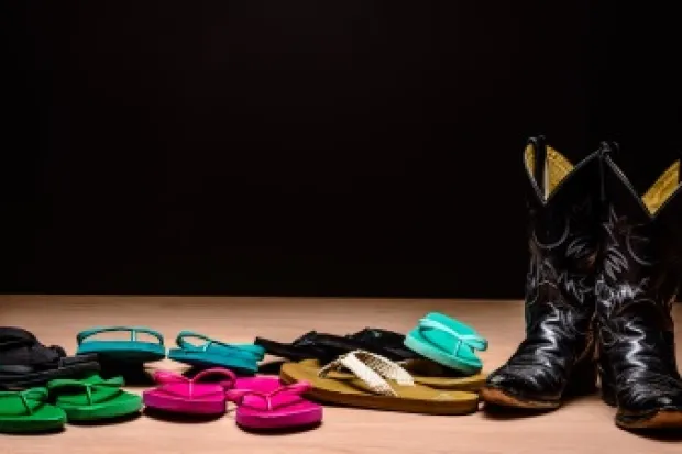 Pile of multicolored flip-flops and set of black cowboy boots