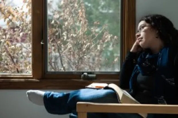 a woman with a Bible on her lap looking through a window