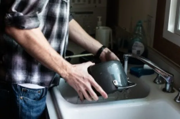 Man washing dishes in kitchen sink