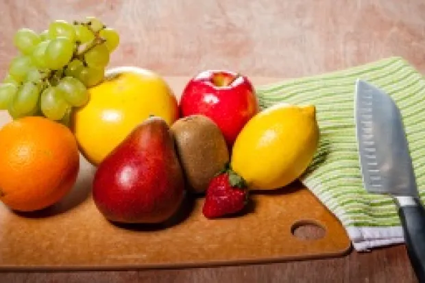 Variety of fruit on cutting board beside kitchen knife and towel