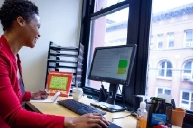 Woman sitting at computer in office overlooking cityscape