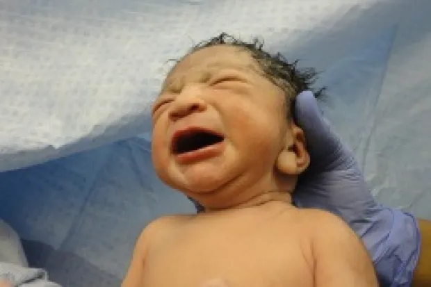 Closeup of newborn crying held by doctor