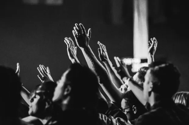 A black and white photo of many hands raised in worship