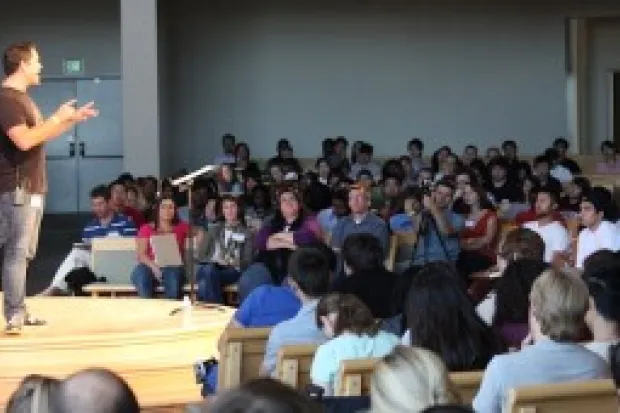 a large group of students listening to a man speak 