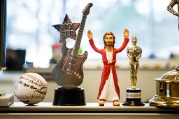 Jesus action figure standing between various golden trophies and autographed baseball