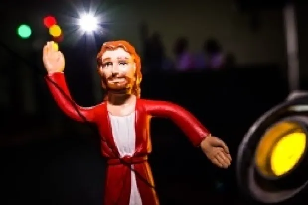 Jesus action figure standing in spotlight with dark background