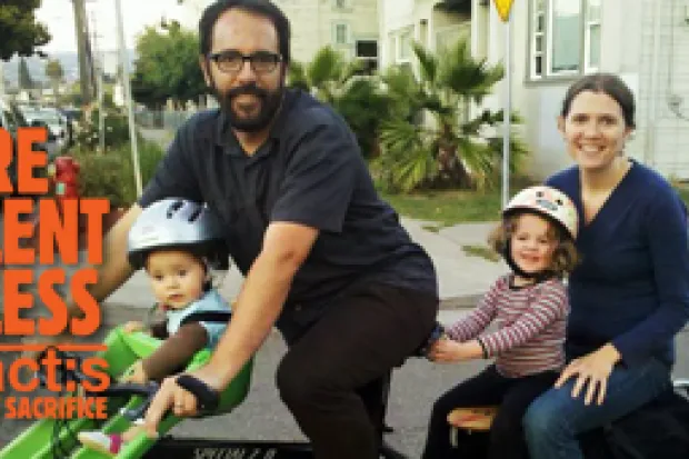 Mother and father posing with two young children outside of home with the label: Relentless Acts of Sacrifice