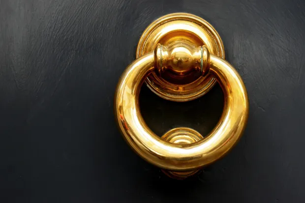 a gold door knocker on a black door