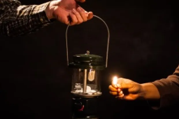 a person lighting a lantern in the dark.