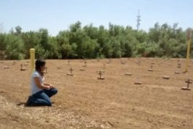 A person kneeling in a dusty desert landscape