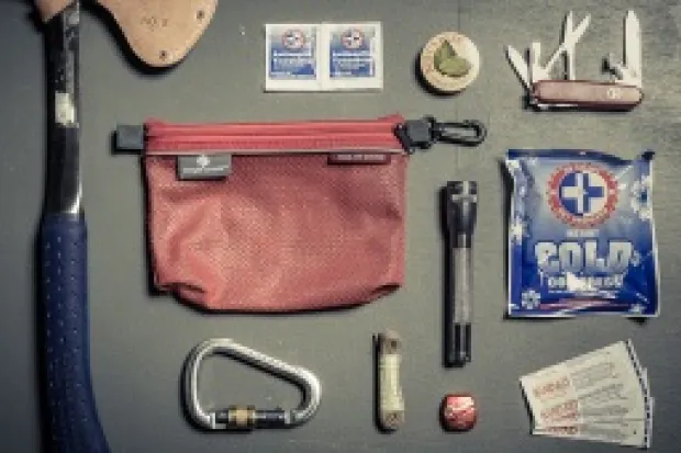 Bunch of survival gear including hatchet, carabiner, ice pack, and bandages 