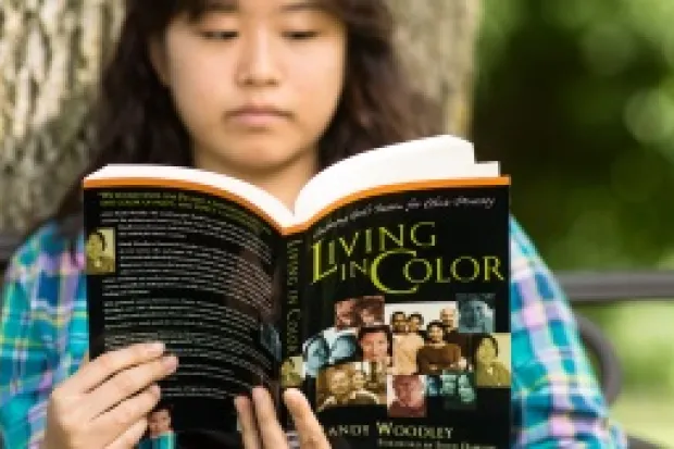 Native female student reading Living in Color book outside