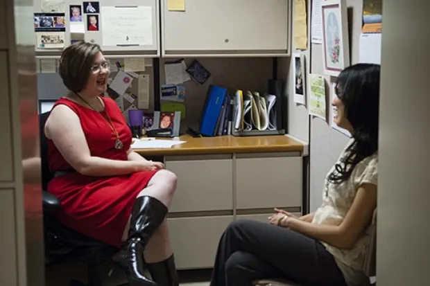 Two women having conversation in office cubicle