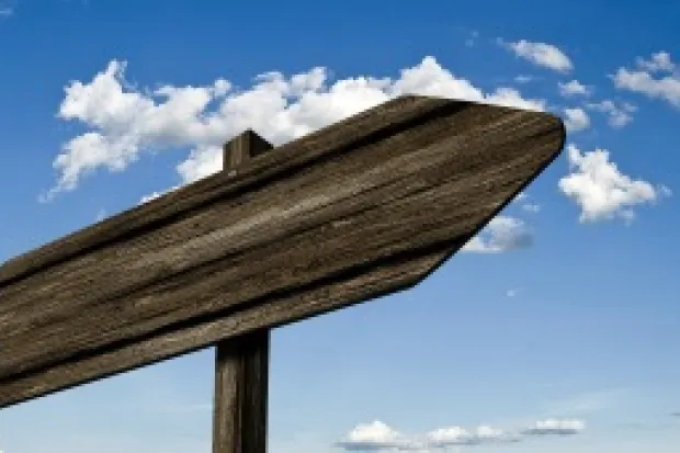 A wooden signpost in front of a blue-sky backdrop.