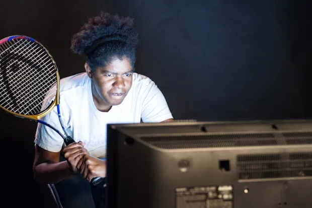 a woman holding a tennis racket and watching television