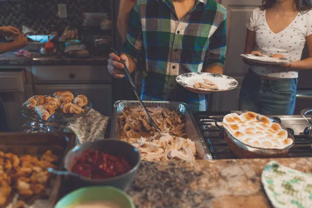 Person picking food on a tray from a Thanksgiving feast