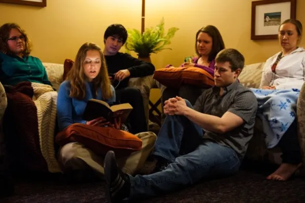 Group of students sitting on couch listening to Scripture being read