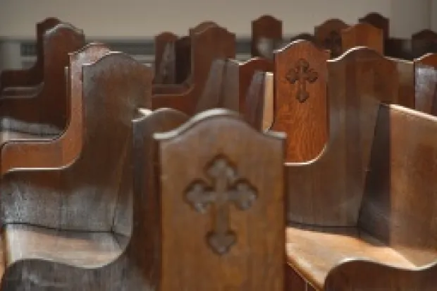 wooden pews with a cross engraved on their side.