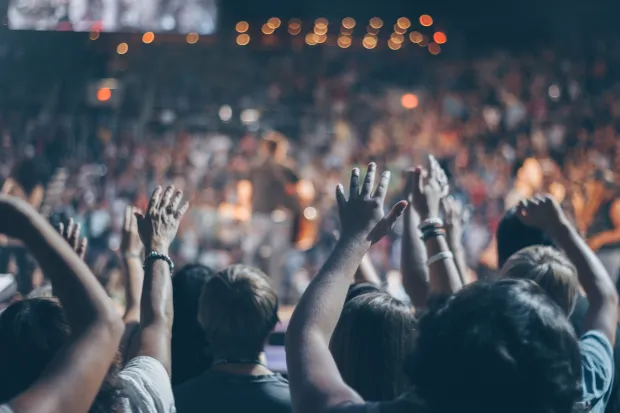 Group of people in auditorium with hands raised worshiping