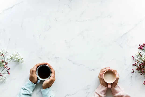 Closeup of two sets of hands holding coffee mugs