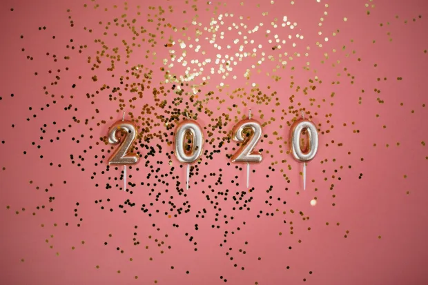 Gold balloons spelling out "2020" over a pink background with confetti