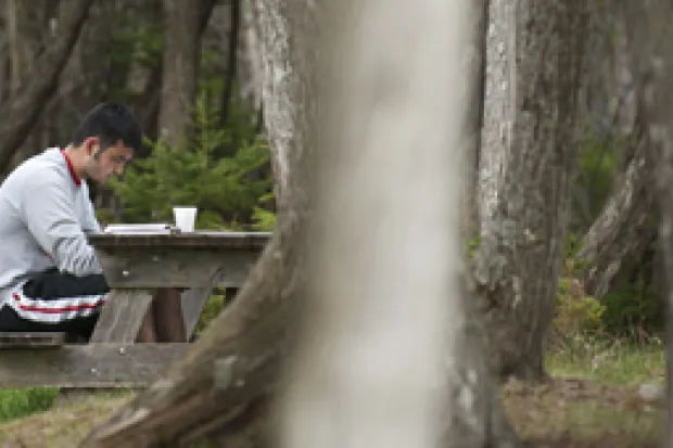 Man sitting at picnic table in park reading