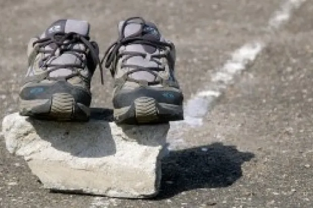 Pair of running shoes sitting on top of rock on the pavement