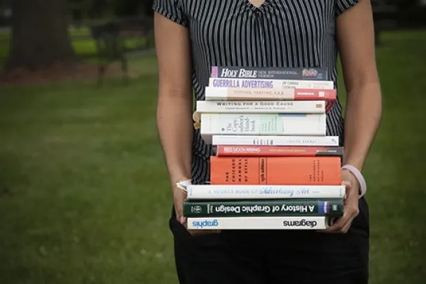 Person holding massive stack of textbooks