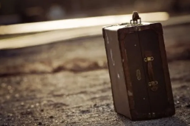 a leather suitcase resting on asphalt