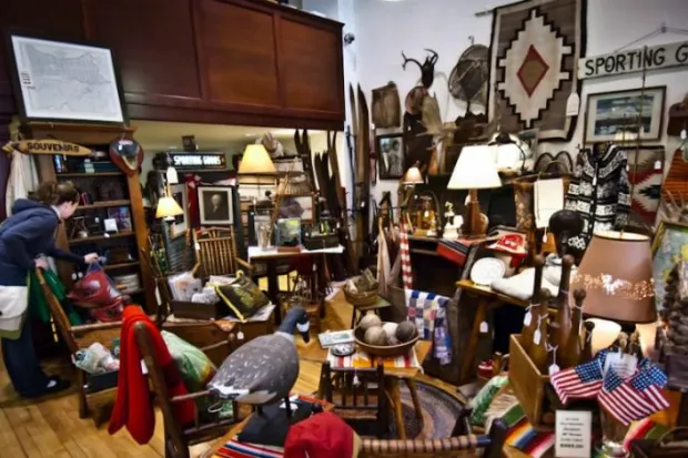 Woman shopping at antique store full of furniture and random knickknacks