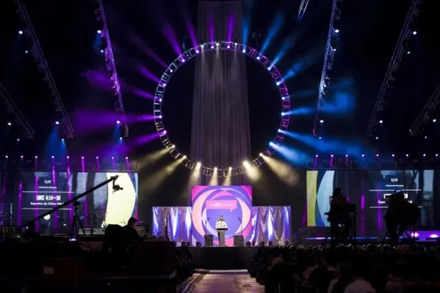 Stage of Urbana with huge ring of colorful lights, bright stage pieces, and shadowy background 