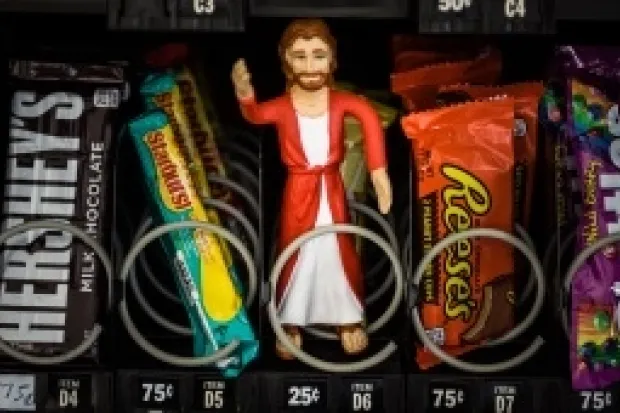 Jesus action figure sitting in vending machine next to candy bars