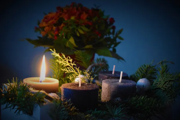 Four candles in a wreath surrounding a spring of poinsettia