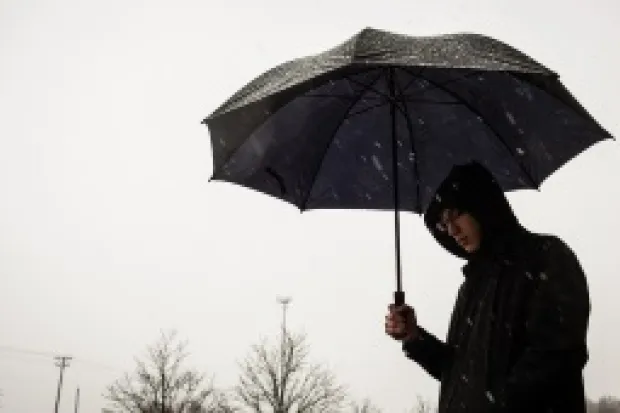 Person wearing raincoat, holding umbrella