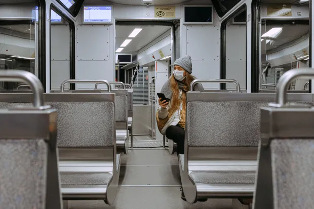 a woman wearing a mask sitting alone on a train