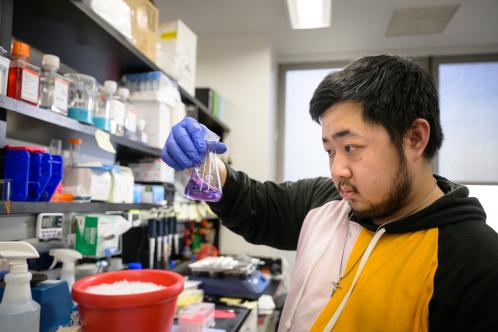 Man in lab reviewing a sample in a beaker