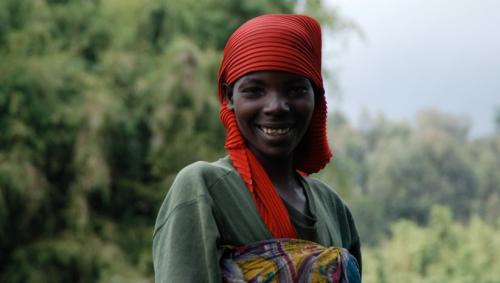 Young African woman smiling wearing red headwrap and green dress
