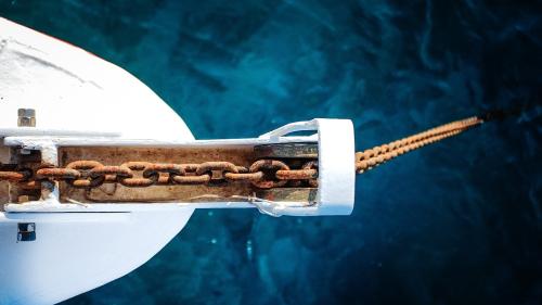 Looking down on a boat anchor lowered into the water