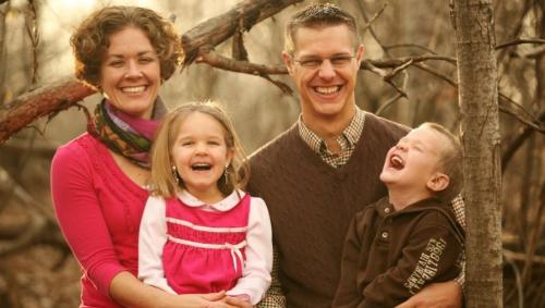 Family photo of mother and father with two small children laughing