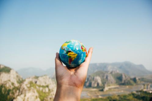 Hand holding small globe against mountain landscape