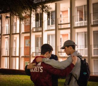 three male students praying for each other on campus