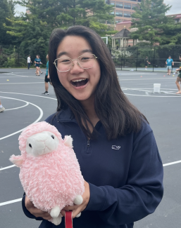 Sam smiling and holding stuffed lamb toy named Gerald (the unofficial InterVarsity mascot).