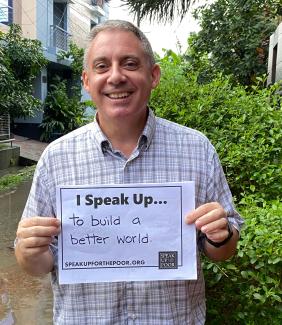 Man smiling and holding a sign that says "I speak up...to build a better world"