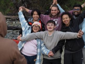 diverse group photo of people making a star shape with their arms and hands linked