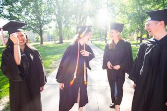 Group of students laughing, wearing caps and gowns